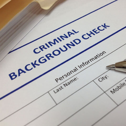 Image of a criminal background check document with a pen and file folder sitting on top of it.