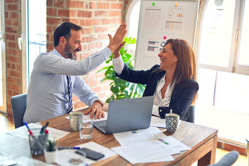 Picture of a mand and a woman in a meeting high-fiving.