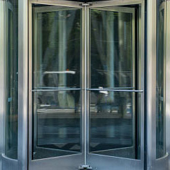 Image of revolving doors that have silver metal framework and glass in the framework.